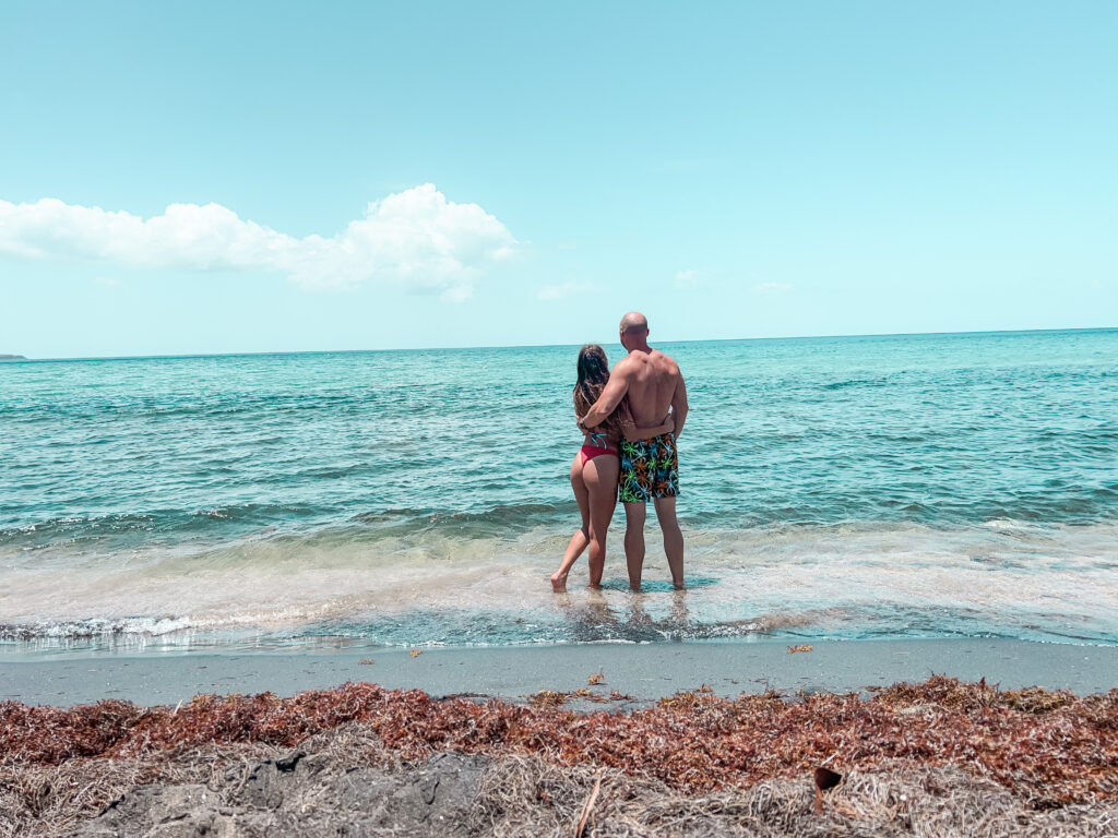 Couple standing on the beach facing the ocean