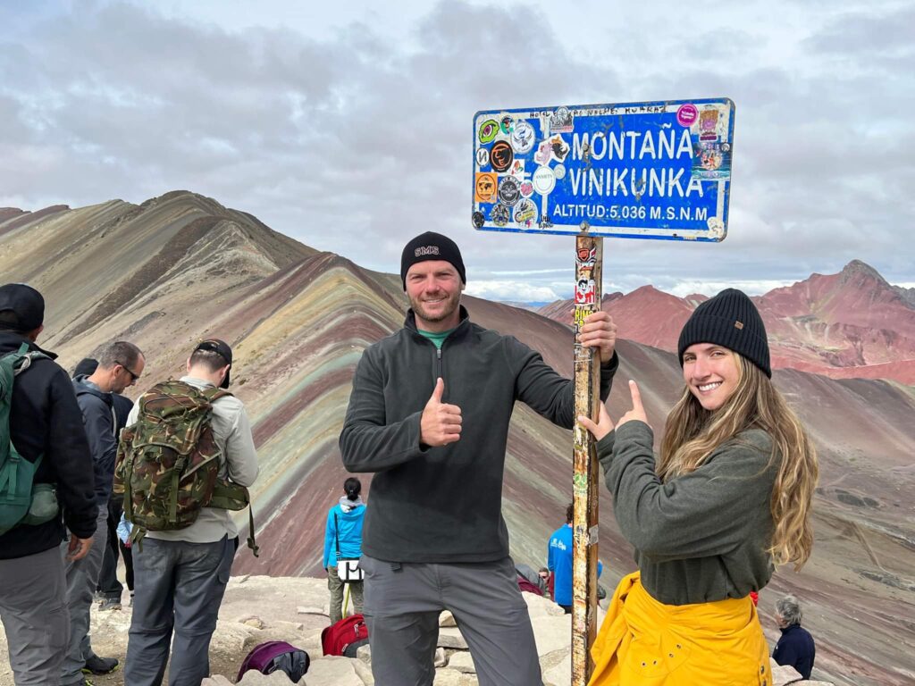 Standing with the sign at the very top of Rainbow Mountain