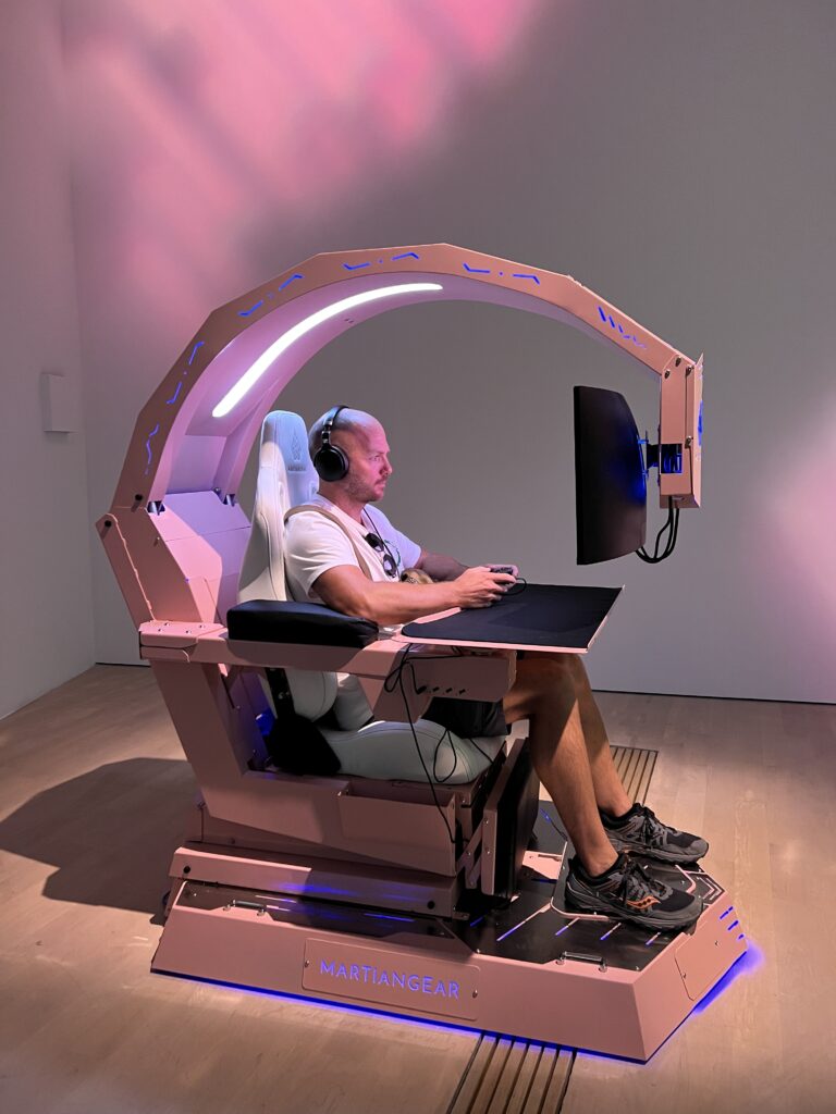 Man sitting in a high tech looking chair playing a video game. 