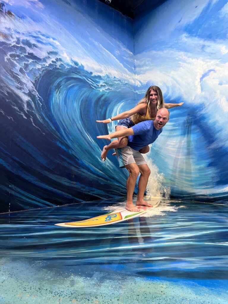 3d art woman on man's back appearing to be surfing. 
