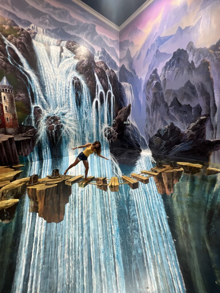 3D art girl appears to be on a rope bridge over a waterfall