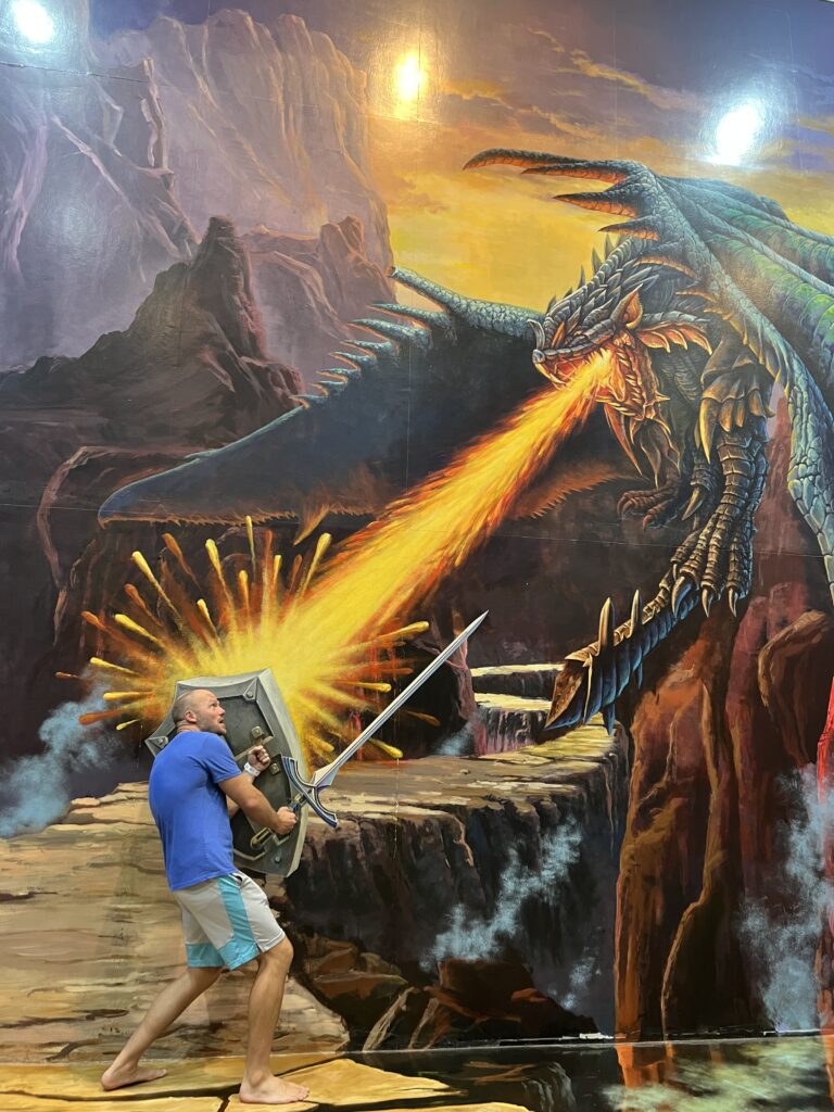 3d art man appears to be holding a sword and shield while battling a dragon breathing fire.