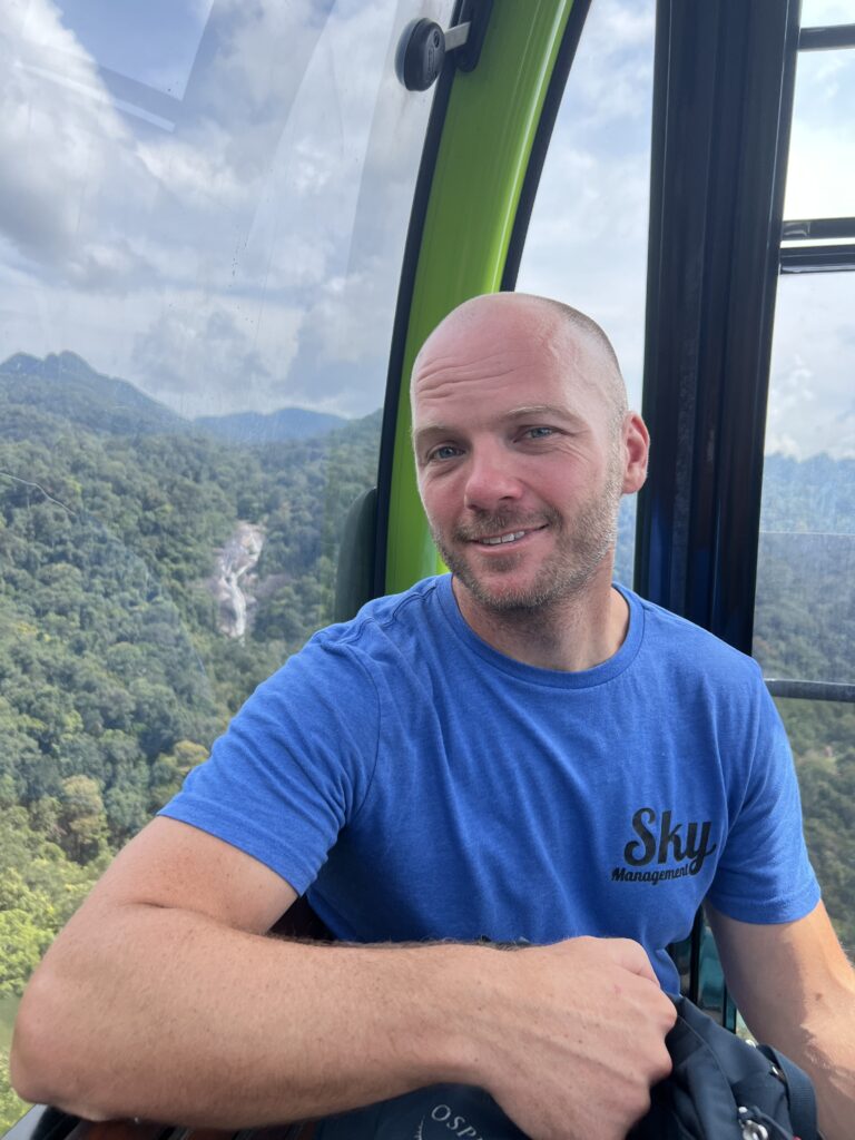 Man sitting in SkyBridge Cable car with Seven Falls waterfall in the background