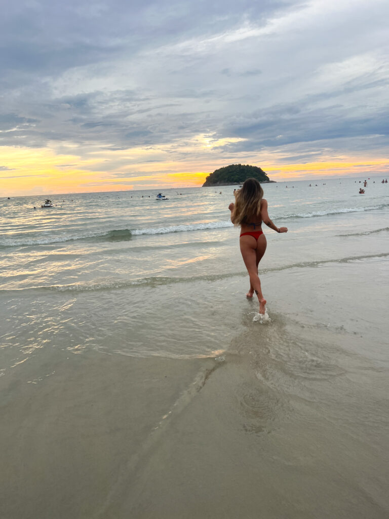 Girl running into the water on Kata Beach with a beautiful sunset. 