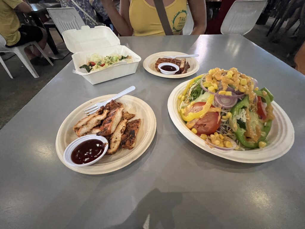 Variety of food including grilled chicken and a large salad from the market